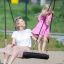 Femme et enfant sur une balançoire simple BNS 90 cm dans une aire de jeux.