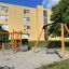 Single Swing (BNS 90cm) dans une aire de jeux près d'immeubles d'appartements