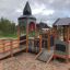 Campanille playground castle avec toboggans et éléments d’escalade dans un parc.