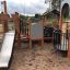 Campanille playground castle avec toboggan et structures d’escalade sur surface sablonneuse