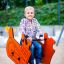Enfant jouant sur Bulldozer rocking dans une aire de jeux.