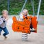Des enfants jouent sur un ressort à bascule Bulldozer rocking dans une aire de jeux.