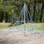Small Powerclimber climbing net dans un parc avec des arbres en arrière-plan.