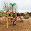Britta's Playhouse structure de jeu extérieure en bois avec toboggan, filet d'escalade et maisonnette colorée dans