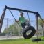 Garçon se balançant sur Double Tyre double swing dans l'aire de jeux.