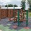 Spillikins wooden playhouse sur une aire de jeux avec structures d'escalade et revêtement de sécurité en caoutchouc.