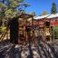 Cabane de jeu en bois avec murs d'escalade et toboggan dans un terrain de jeu.