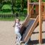 Enfant jouant sur Hexagon Modern Nature single slide dans une aire de jeux.