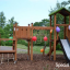 Triangle Modern Nature wooden playhouse with slide dans un parc décoré de ballons colorés