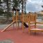 Triangle Modern Nature wooden playhouse with slide dans une aire de jeux.