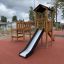 Triangle Modern Nature wooden playhouse with slide sur l'aire de jeux