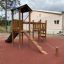 Triangle Modern Nature wooden playhouse with slide sur une aire de jeux extérieure