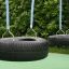 Wooden Tire double swing avec des pneus noirs et des cordes bleues dans une aire de jeux