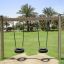 Wooden Tire double swing dans un parc avec des palmiers en arrière-plan.