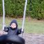 Enfant assis sur un Wooden Tire double swing dans une aire de jeux.