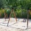 Triple swing dans une aire de jeux avec du sable.