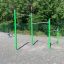 Barres de traction en métal pour l'exercice en plein air dans une aire de jeux avec des poteaux verts et trois hauteurs différentes.