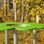 Clover Play Table dans un parc avec dessus vert et pieds en métal.