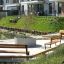 Espace de sièges de parc présentant Ryga Bench w/ Backrest et d’autres bancs dans un cadre résidentiel moderne