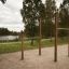 Barres de traction extérieures pour l’entraînement dans un parc avec des arbres et un lac en arrière-plan.