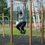 Femme faisant de l’exercice sur des barres de traction dans une salle de sport en plein air.