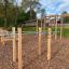 Station de fitness extérieure Bars I avec des éléments en bois et en métal dans un parc.