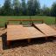 Banc à abdominaux en planches de bois, placé en extérieur sur une surface en copeaux de bois, avec de la verdure et des arbres