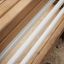 Banc à abdominaux avec cadre en bois et barres blanches pour l’exercice en extérieur.