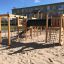 Structure de jeu en bois avec filets d’escalade et toboggan tunnel, Romping Cottage.
