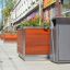 Chicago bin à côté d’une grande jardinière en bois sur un trottoir de ville.