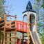 Alcazar playground castle avec toboggan et structure d’escalade dans un parc.