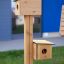 Bird feeder avec deux nichoirs en bois montés sur un poteau vertical.
