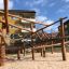 Maison de jeu en bois Sonora sur une aire de jeux sablonneuse avec cordes d’escalade et poutres en bois.