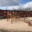 Maison de jeu en bois Sonora dans une aire de jeux sablonneuse
