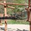 Cabane de jeu en bois Sonora avec poutres en bois et pont en filet dans une aire de jeux extérieure.
