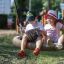 Des enfants assis sur un Silver Double Swing (BNS90) dans une aire de jeux.