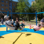 Équipement de jeu Six Arm Swing Silver avec des enfants jouant sur les balançoires dans un parc ensoleillé.