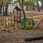 Équipement de terrain de jeu extérieur pour enfants dans un parc entouré d’arbres - la maison d’Alice.