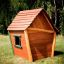 Maison de jeu en bois Crooked House sur un champ herbeux.