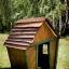 Maison de jeu en bois nommée Crooked House dans un jardin.