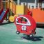 Équipement de aire de jeux rouge Copter rocking avec aire de jeux et toboggan en arrière-plan.