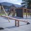 Nature Seesaw en bois sur une aire de jeux moderne avec structures d'escalade en arrière-plan.