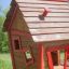 Maison de jeu en bois avec bordures rouges dans une zone herbeuse - Anna's Playhouse.