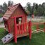 Maison de jeu en bois avec accents rouges et éléments d’escalade de Anna's Playhouse.