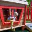 Enfant jouant dans Anna's Playhouse aire de jeux en bois avec accents rouges.