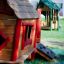 Maisonnette en bois pour enfants avec des accents rouges de la gamme Anna's Playhouse dans une aire de jeux.