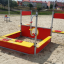 Équipement de aire de jeux Jupiter en rouge et jaune sur le sable.