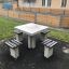 Table d'extérieur en béton Ludo avec quatre sièges fixés dans un parc.