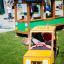 Des enfants jouent dans un bus jouet et un taxi dans une aire de jeux.
