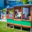 Des enfants jouent dans une structure de jeu en bois en forme de bus.